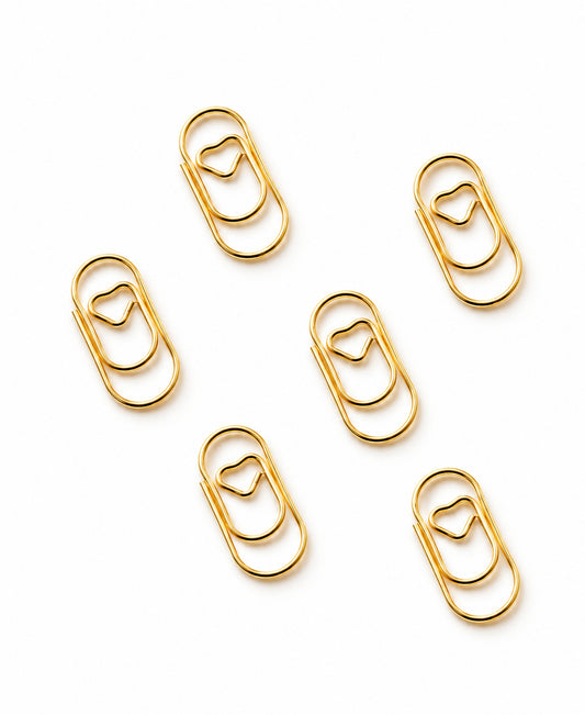 Sechs goldene Mini-Herz-Büroklammern freigestellt auf Weiß